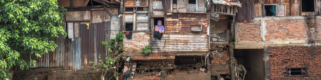 Vrouw kijkt uit het raam van haar woning in Bangladesh, dat onder water is komen te staan door overstromingen