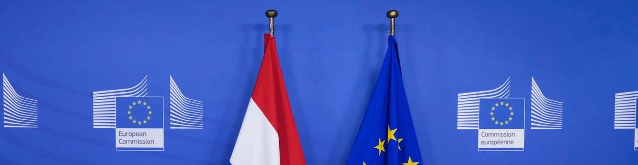 Nederlandse en Europese vlag zij-aan-zij met logo van de Europese Commissie op de achtergrond