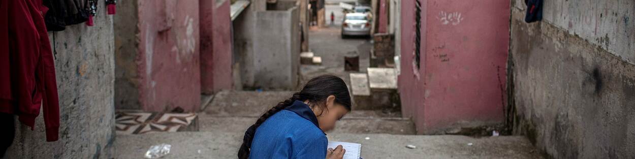 Syrisch meisje schrijft gedichten, op de trap bij haar huis in Amman, Jordanië
